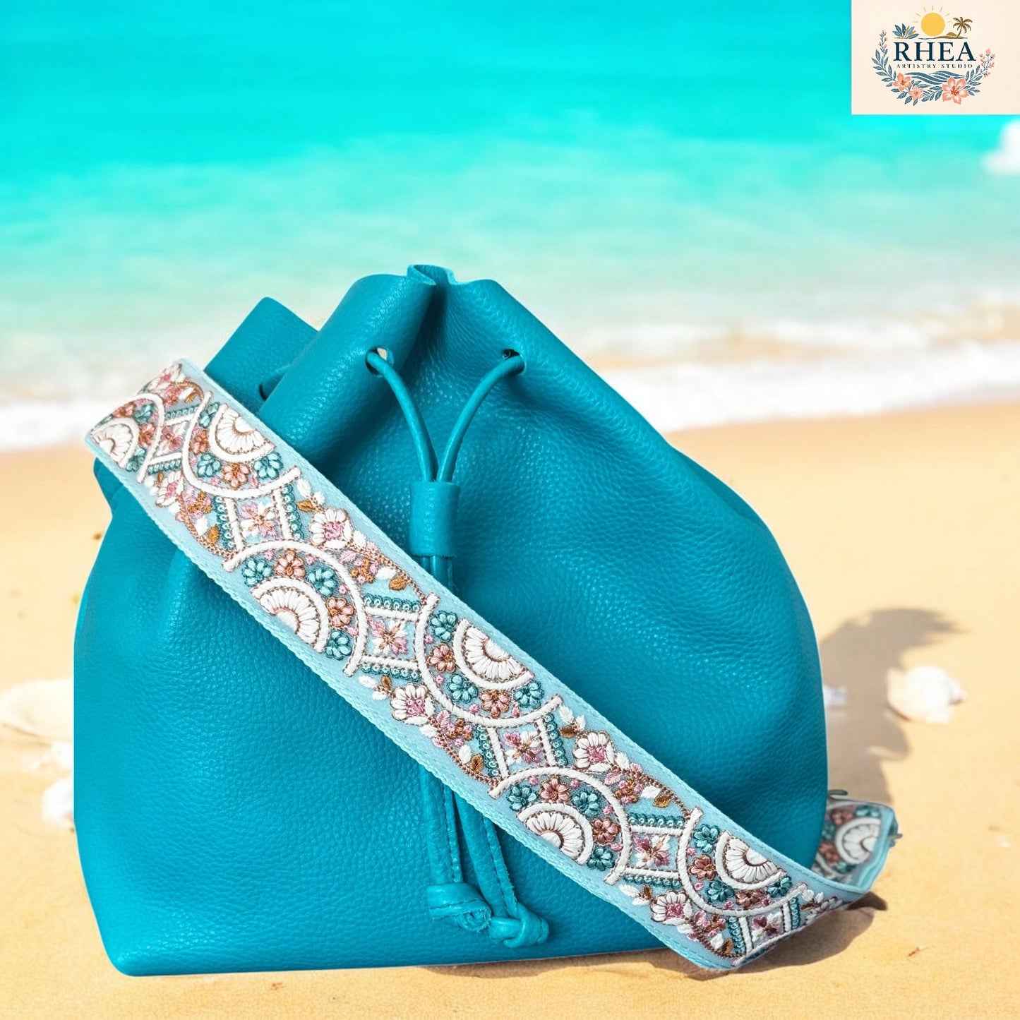 Blue drawstring bag with a decorative strap on a beach