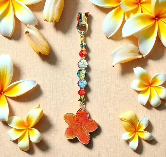 Colorful floral keychain with beads on a beige background with plumeria flowers