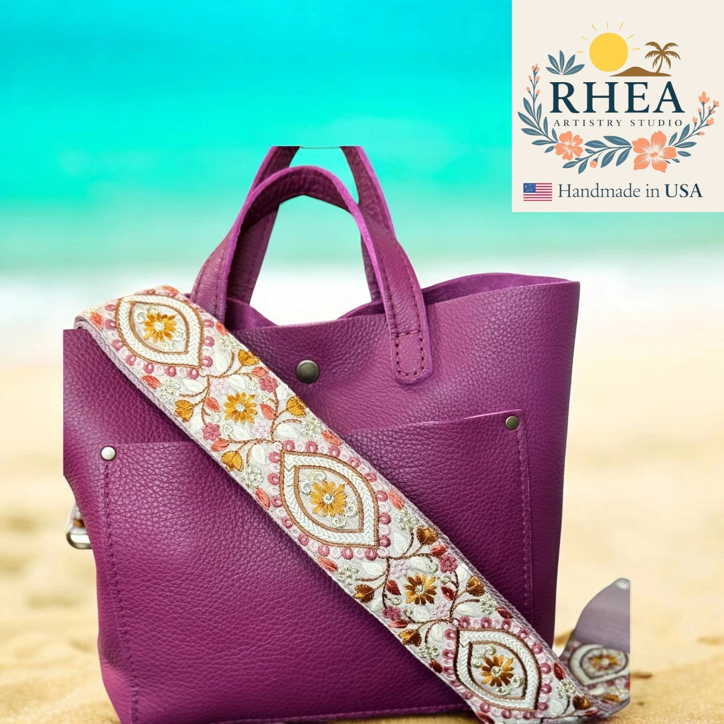 Purple handbag with a decorative strap on a beach background, featuring the Rhea Artistry Studio logo.
