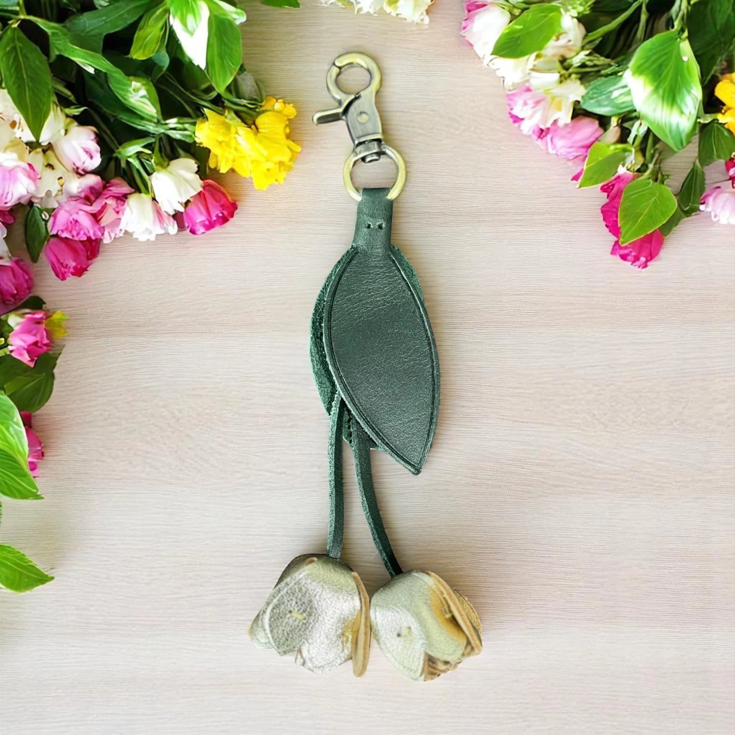 Green leaf-shaped keychain with floral decorations on a light background