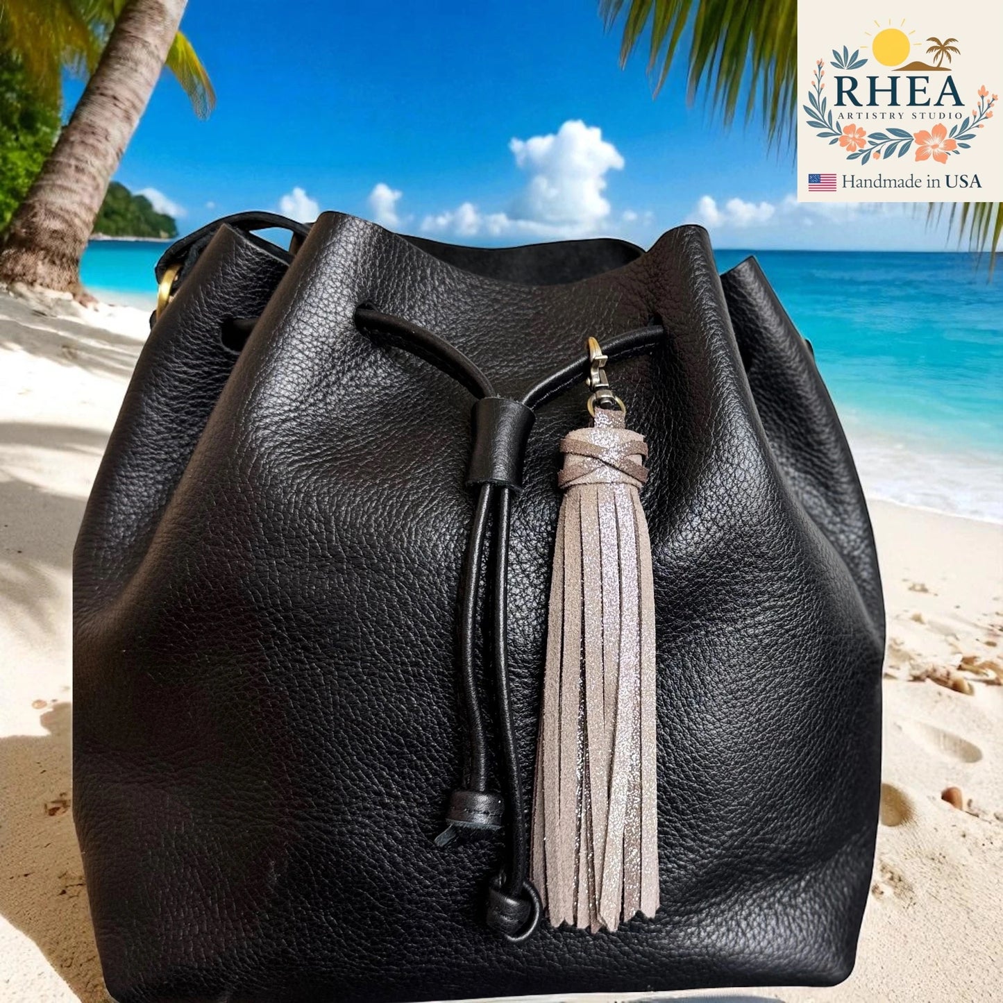 Black leather bag with tassel on a beach with palm trees and blue sky.