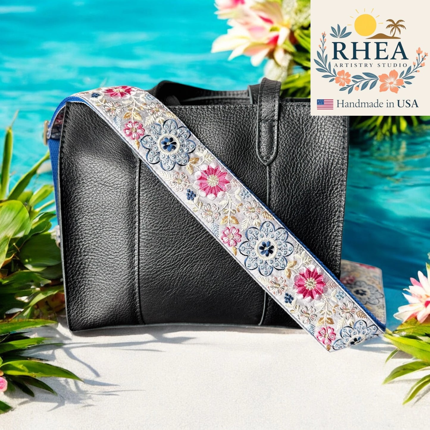 Black handbag with a floral purse strap by RHEA Artistry Studio against a beach background.