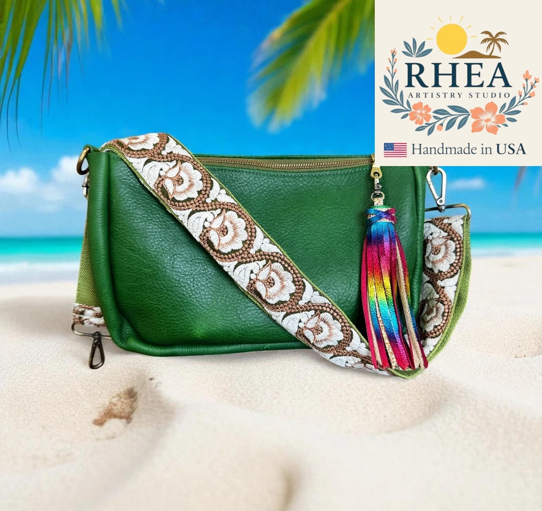 Green handbag with a floral purse strap and colorful tassel on a beach background, featuring RHEA Artistry Studio logo.