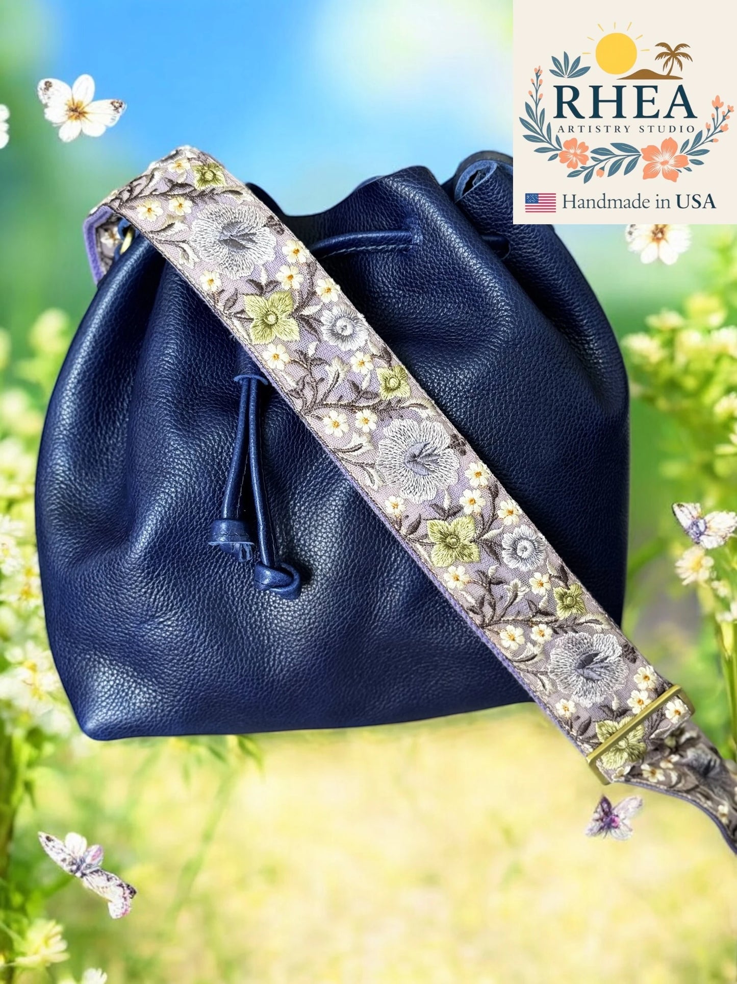 Navy blue leather bag with floral purse strap against a natural background