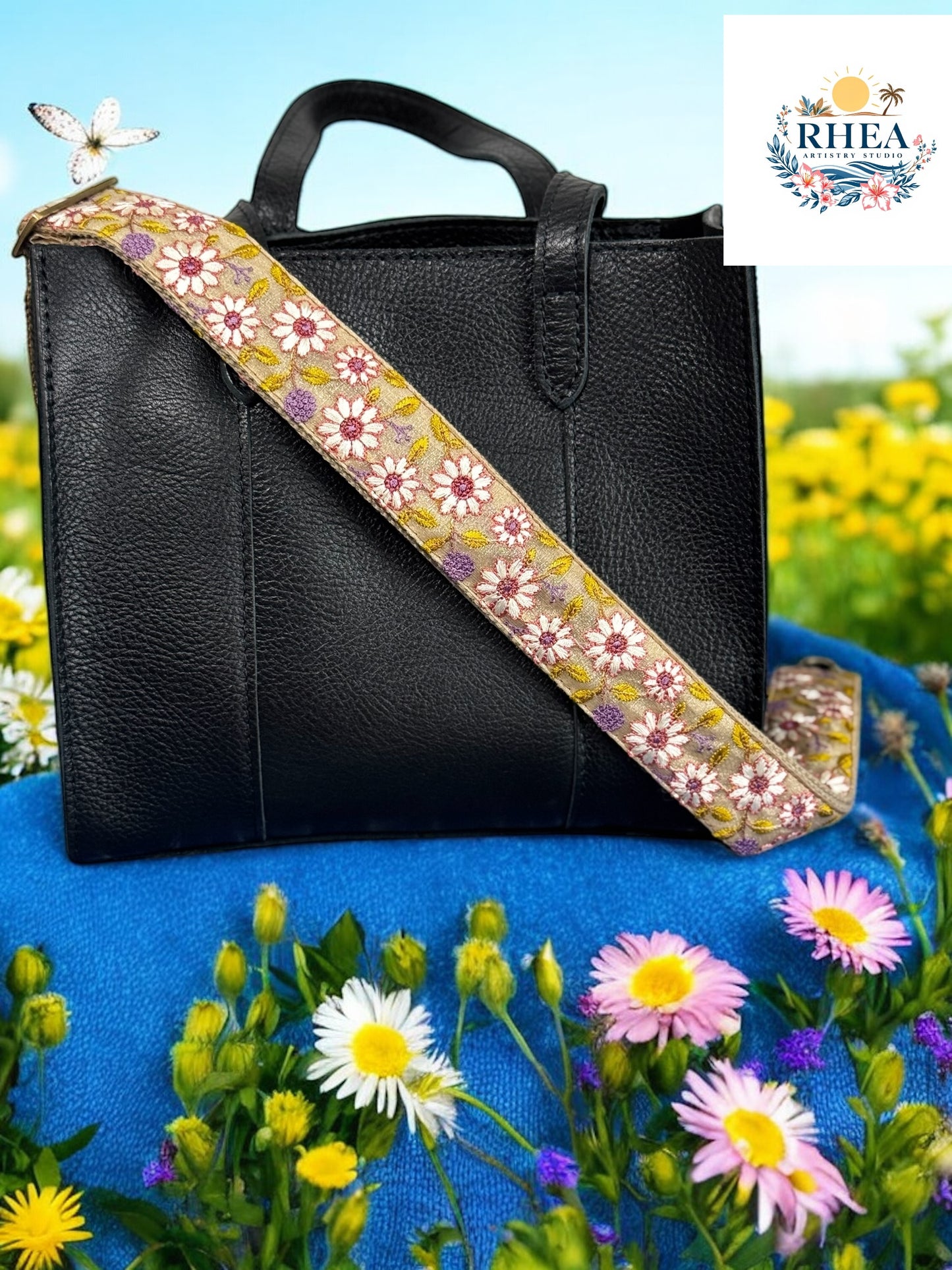 A black purse with a floral embroidered purse strap placed on a surface with flowers in the background.