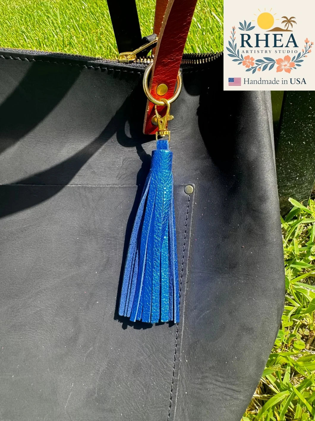 Blue tassel on a black bag with RHEA Artistry Studio branding.