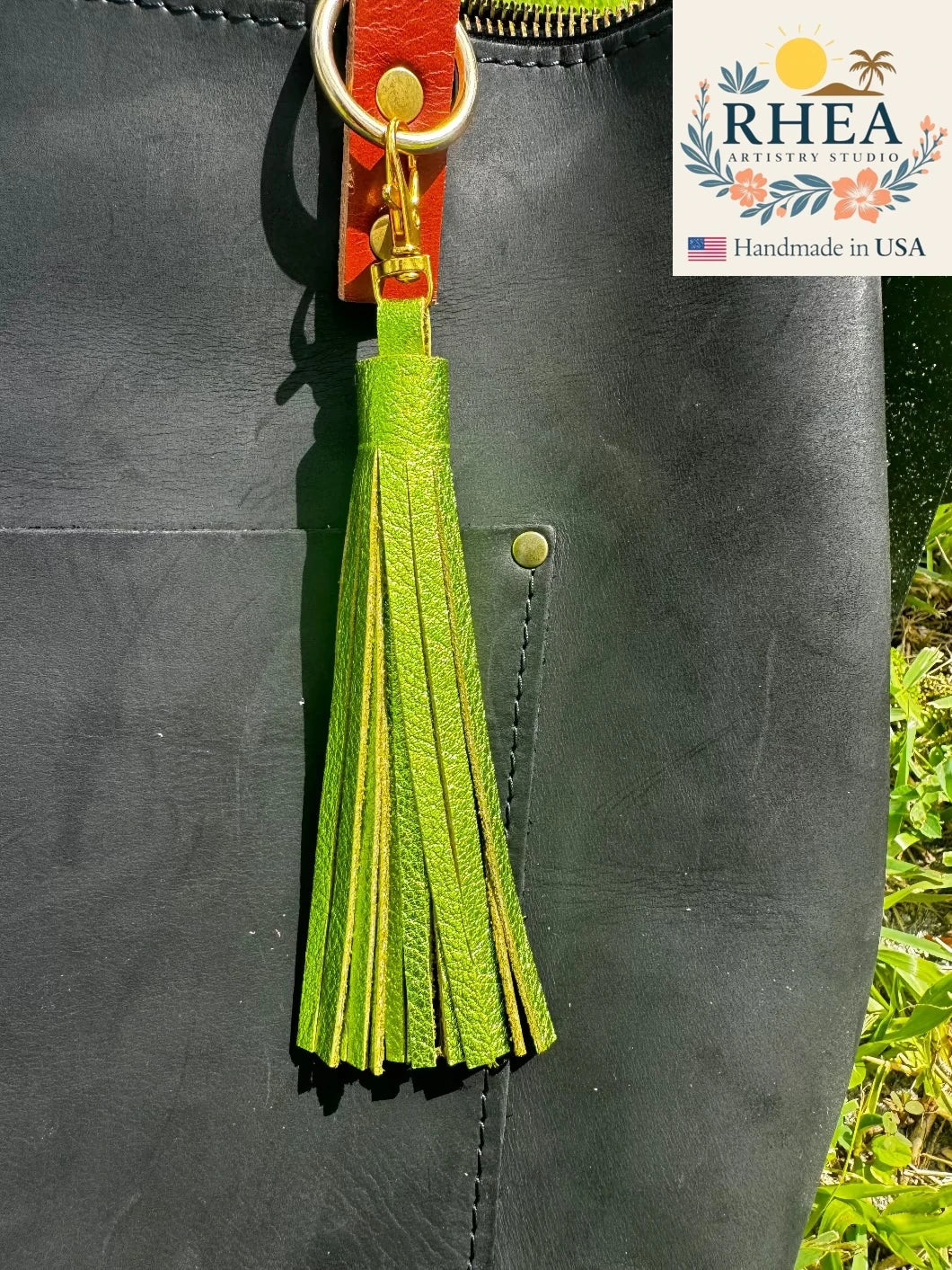 fern Green tassel on a black leather bag with RHEA branding.