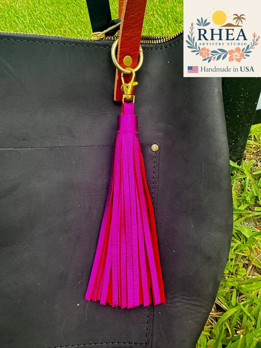 Black leather bag with a pink and red tassel, RHEA brand visible.