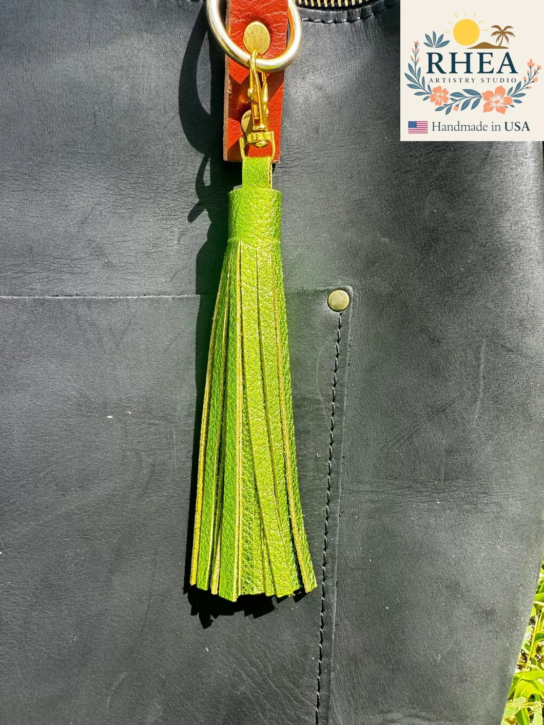 fern Green tassel keychain attached to a leather bag with RHEA branding.