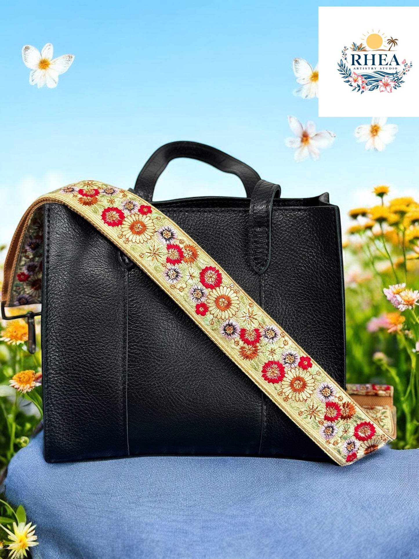 A floral embroidered purse strap in multicolor, attached to a black leather bag with brushed brass hardware.