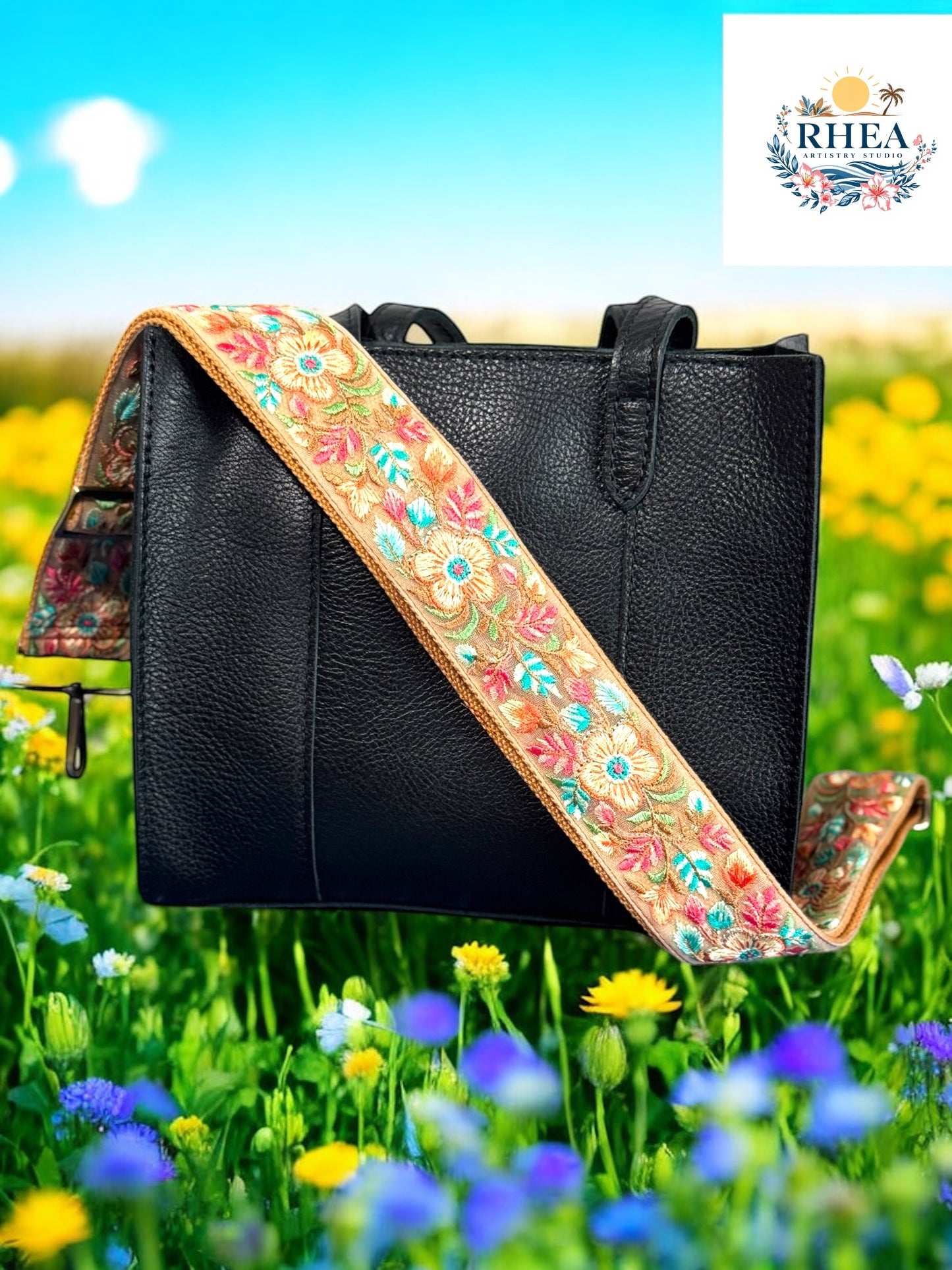 A black purse with a floral embroidered purse strap set against a field of colorful flowers.