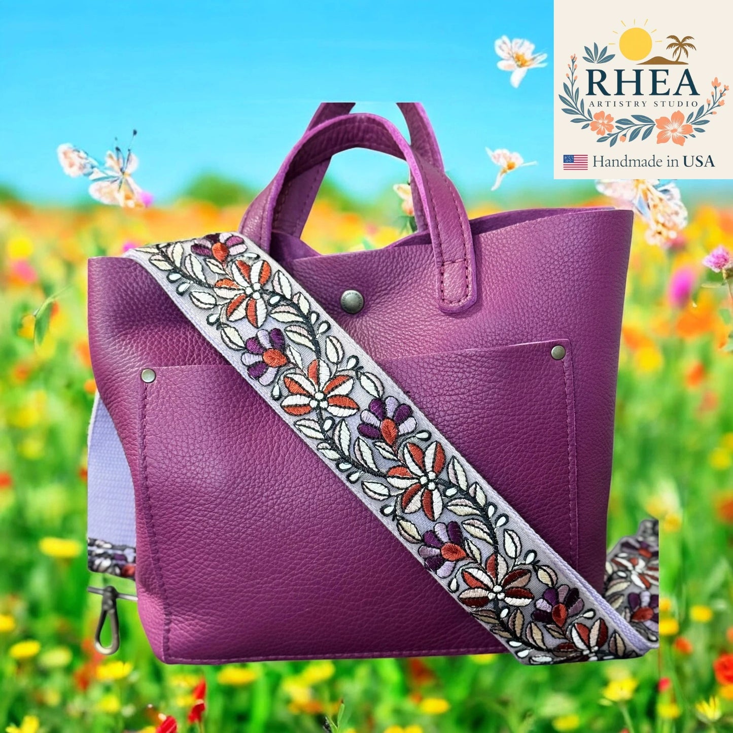 Purple handbag with a floral purse strap against a colorful field background, featuring the RHEEA brand.