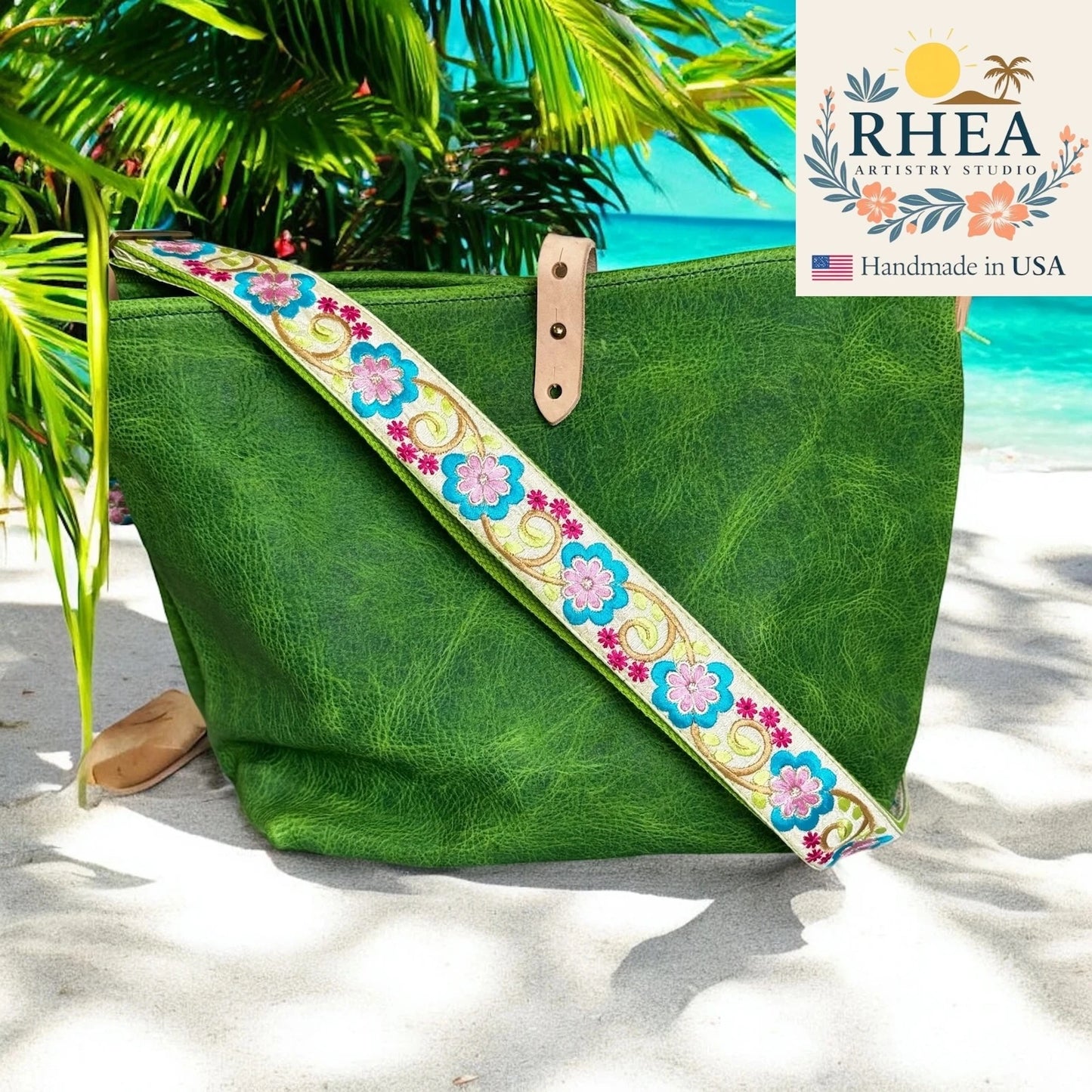 Green bag with a floral purse strap on a beach, featuring the RHEA Artistry Studio logo.