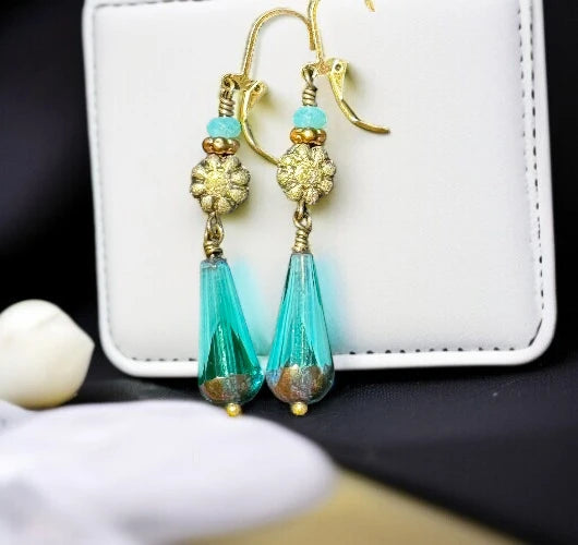 Boho-style long turquoise dangle earrings featuring gold details and faceted glass teardrops.