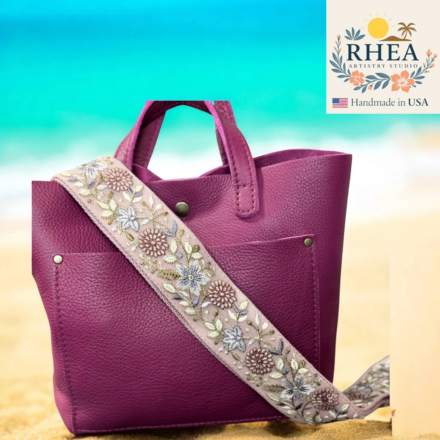 Purple handbag with a floral strap on a beach background, featuring the Rhea Artistry Studios logo.