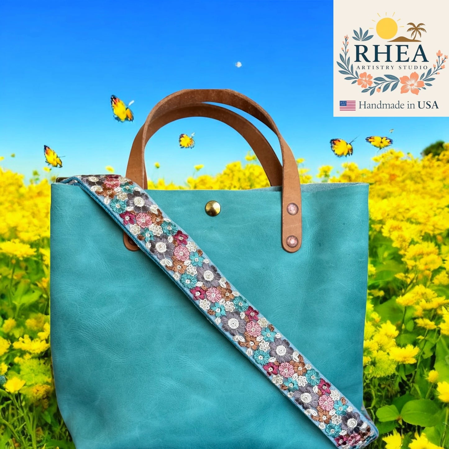 Turquoise tote bag with floral purse strap in a field of yellow flowers, featuring RHEA Artistry Studio logo.