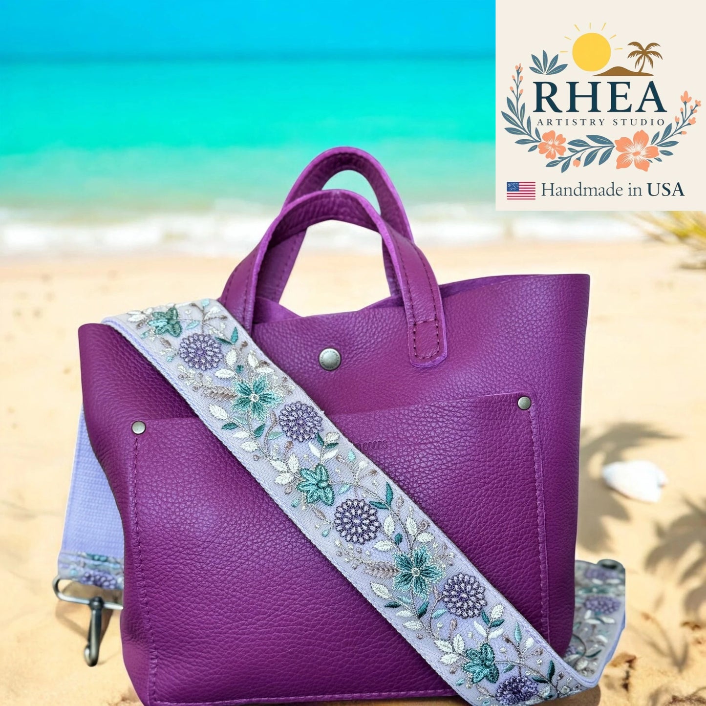 Purple handbag with floral strap on a beach, featuring RHEA Artistry Studio logo.