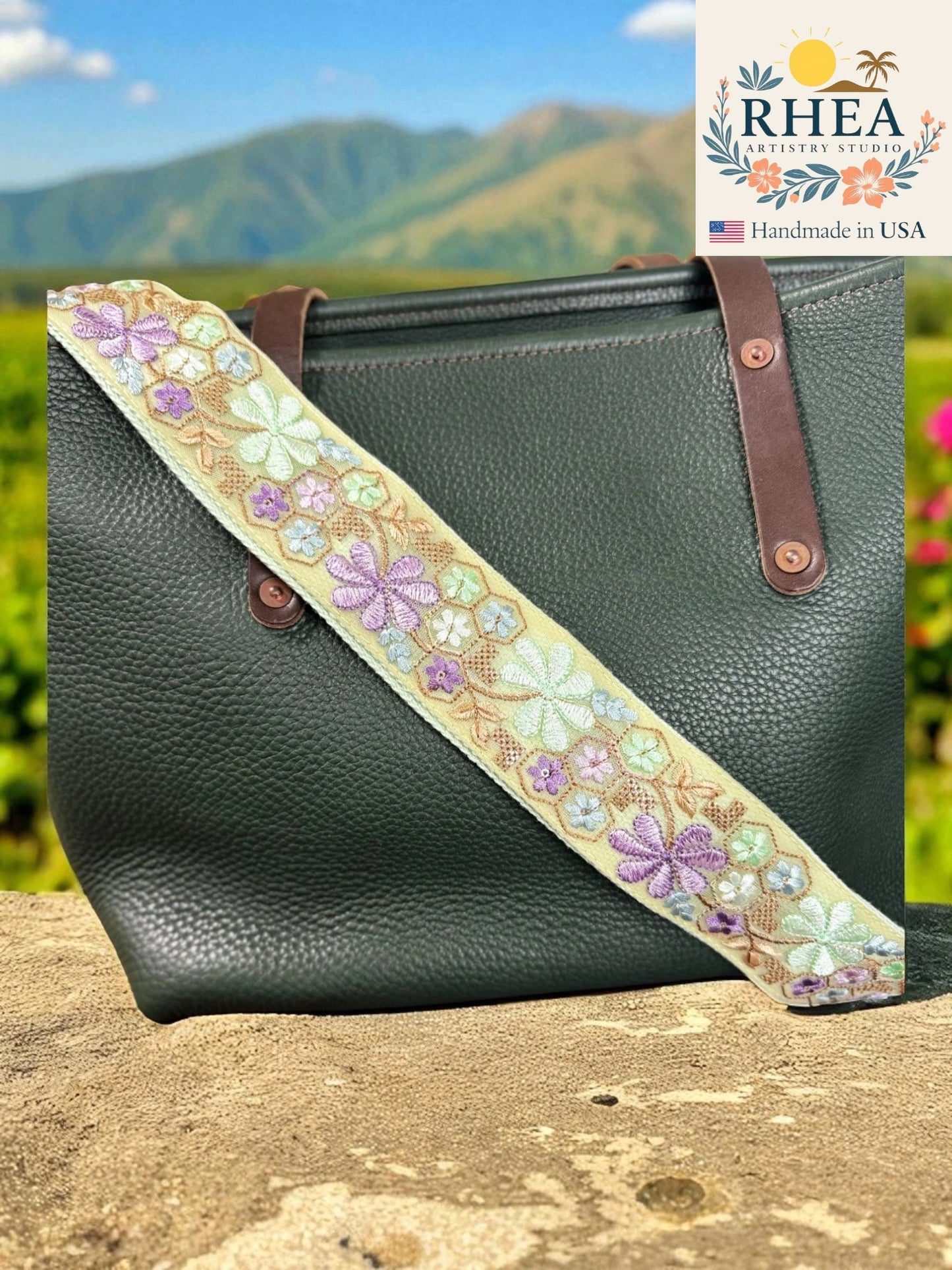 Green handbag with a floral strap against a scenic background, featuring the RHEA brand.
