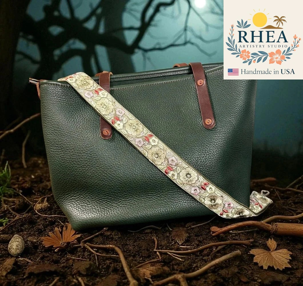 Green leather handbag with floral strap against a natural background, featuring RHEA Artistry Studio logo.