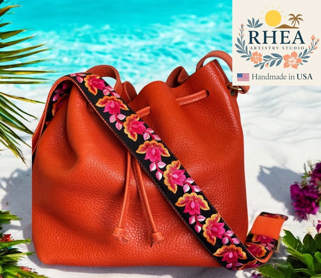 Orange leather bag with floral purse strap by RHEA Artistry Studio on a beach background