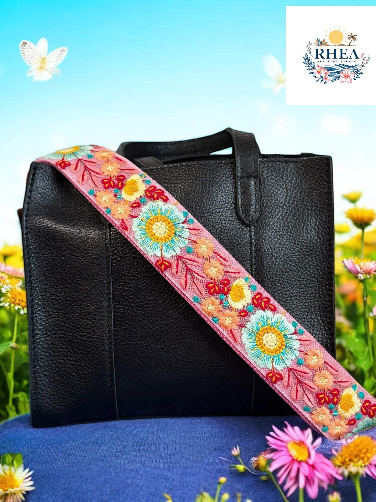 Pink floral embroidered purse strap with sky blue and maroon blooms styled on a black leather bag.