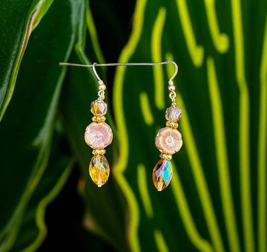 Pair of gold and gemstone earrings on a green leaf background