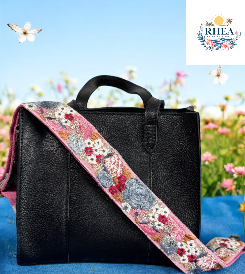 Close-up of black leather bag with wide pink embroidered floral strap featuring oversized blue and red roses by Rhea Artistry Studio.