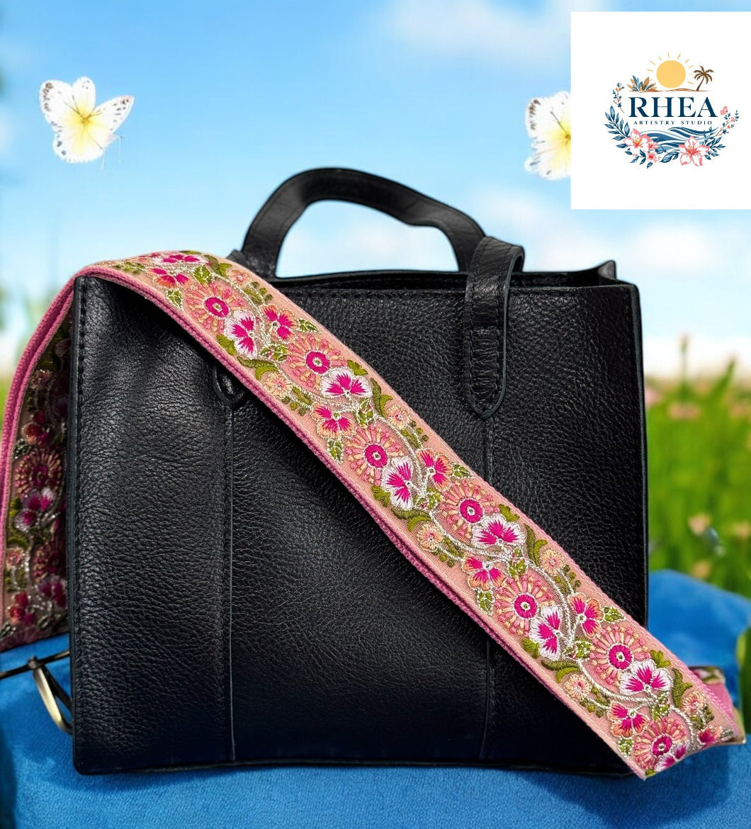 A pink floral embroidered strap placed on a black bag