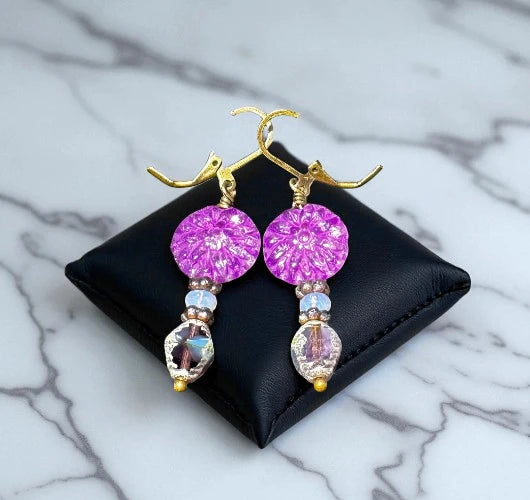 Purple beaded earrings on a black jewelry pouch with a marble background