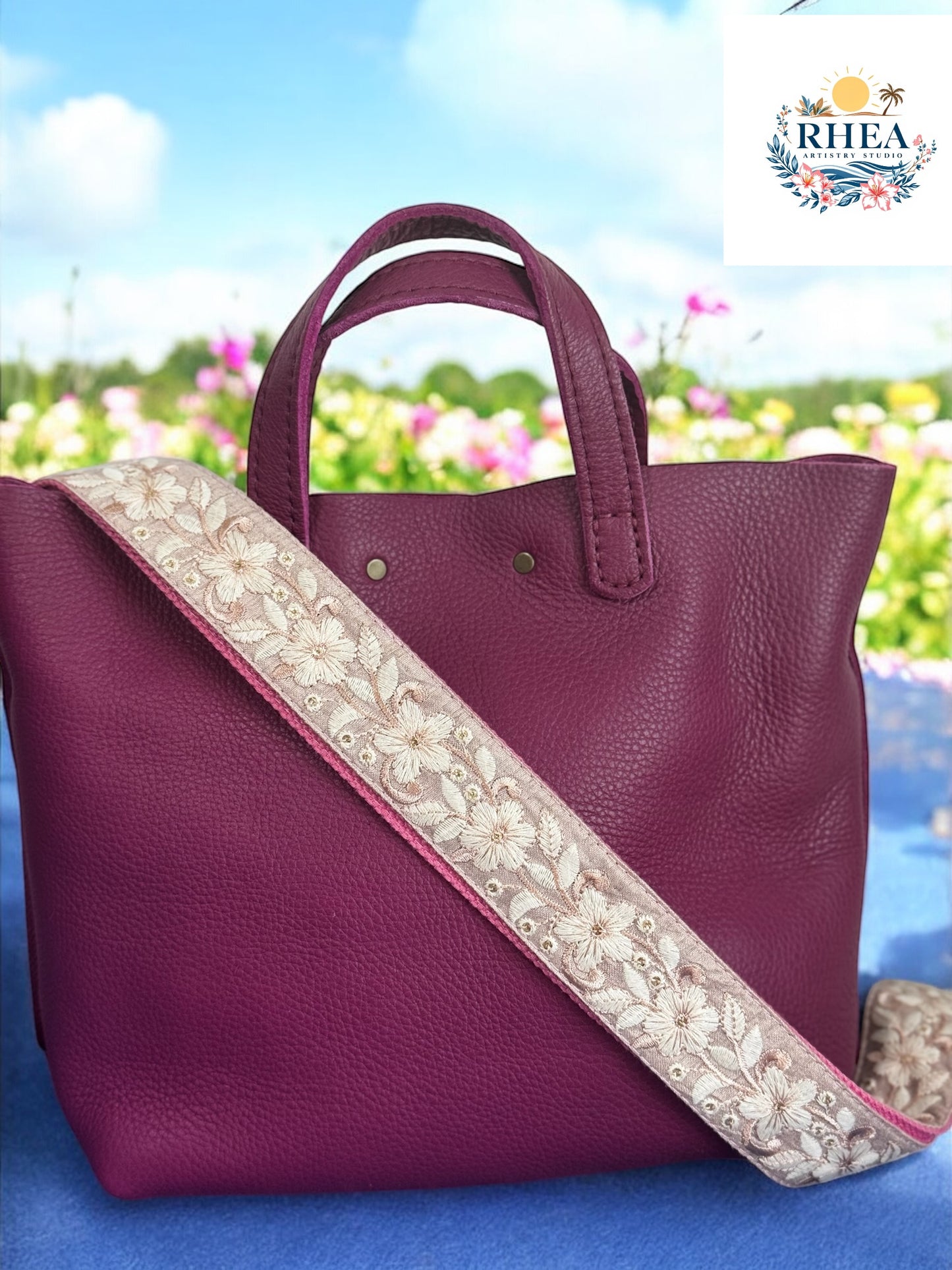 A black purse with a floral patterned strap, displayed against a blue background with floral motifs.