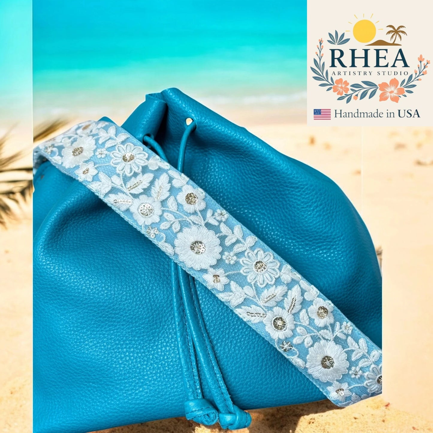 Blue leather pouch with floral purse strap on a beach background, featuring RHEA Artistry Studio logo.