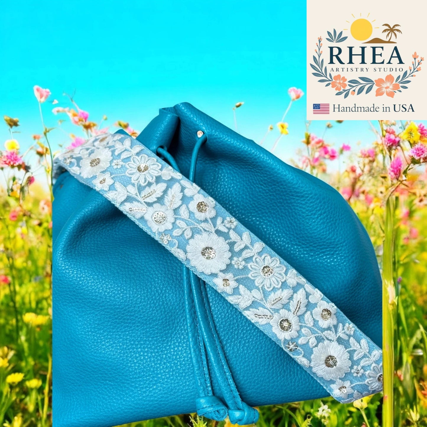 Blue bag with a floral purse strap against a colorful background, featuring the RHEA brand.