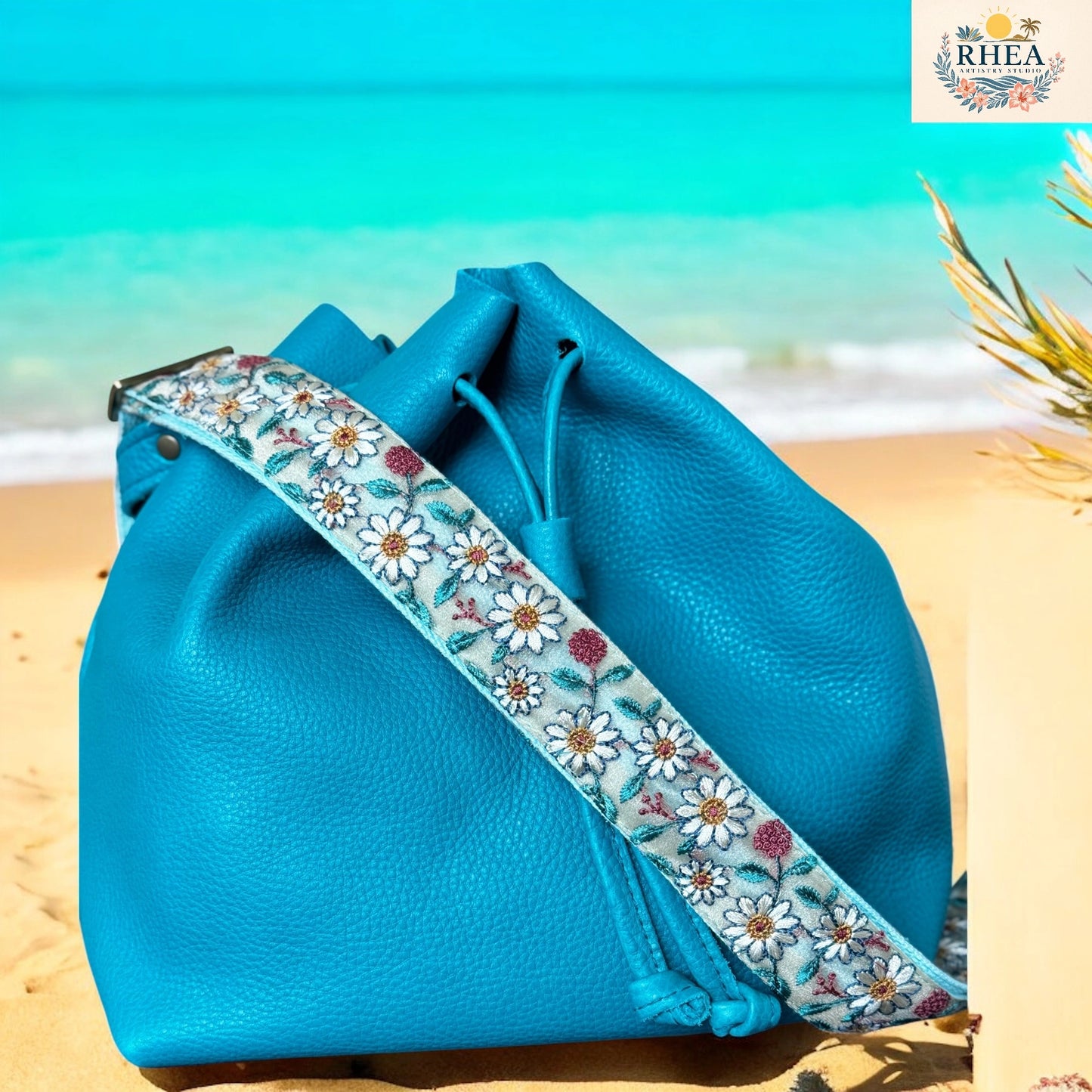 Blue leather bag with floral strap on a beach