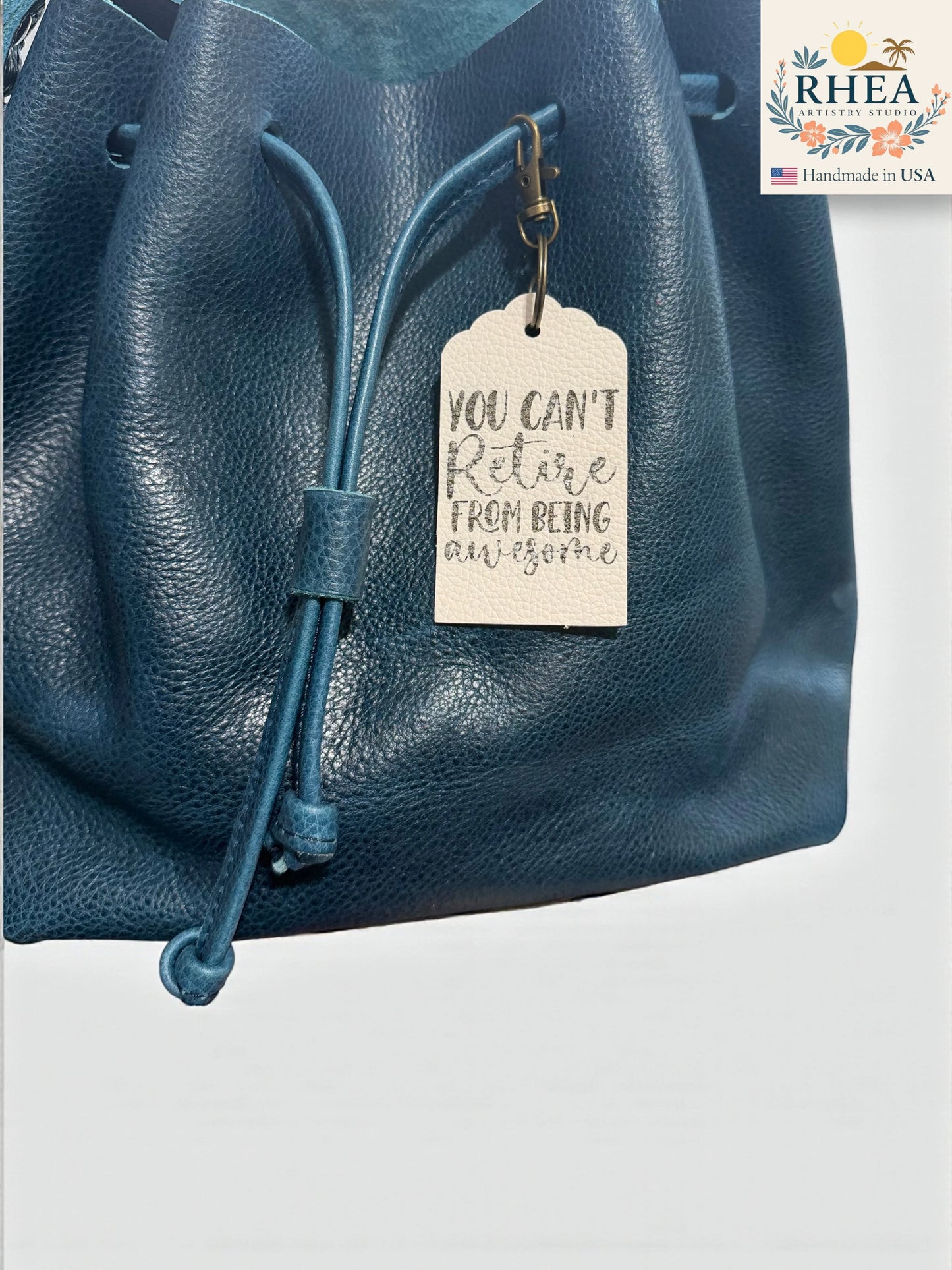Blue leather bag with a motivational tag and RHEEA brand logo.