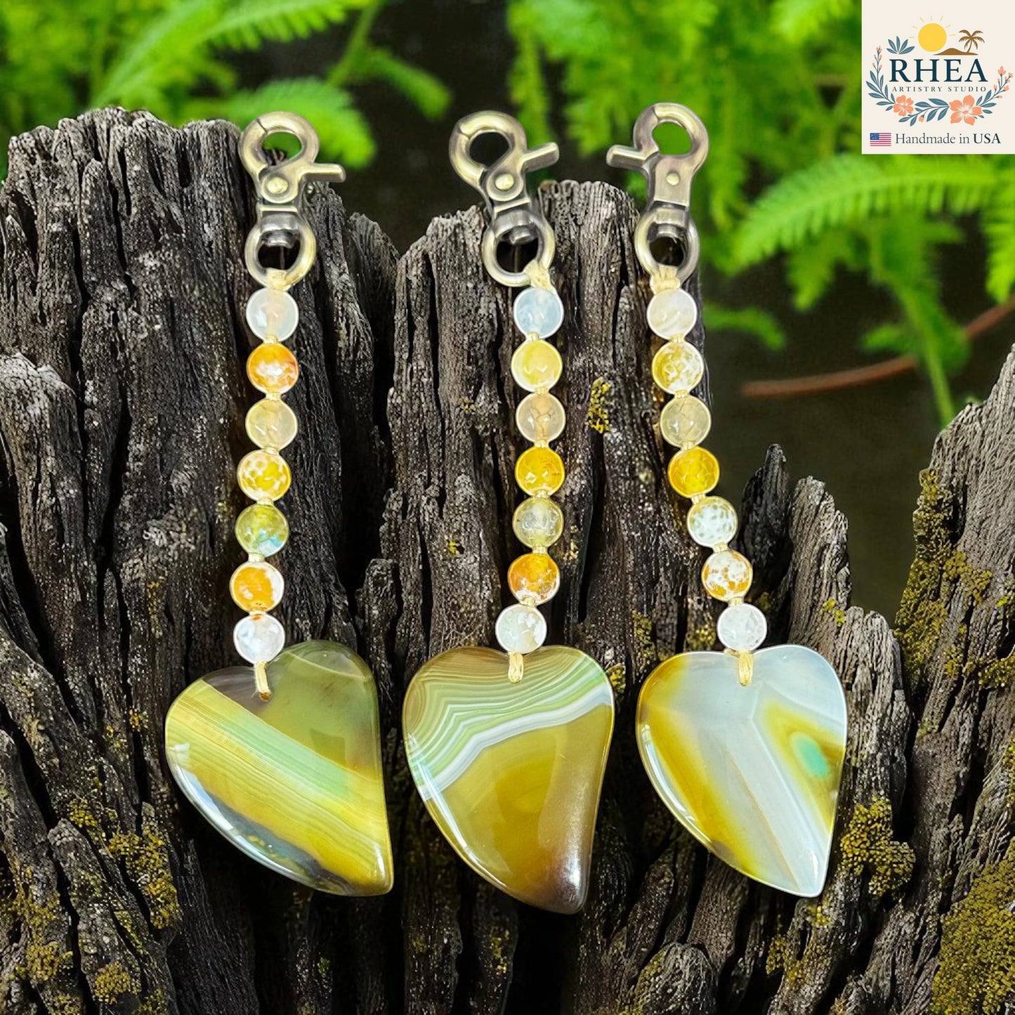Rhea Artistry Studio handmade agate heart bag charms with brushed brass clasps and yellow, white, and green gemstone beads.