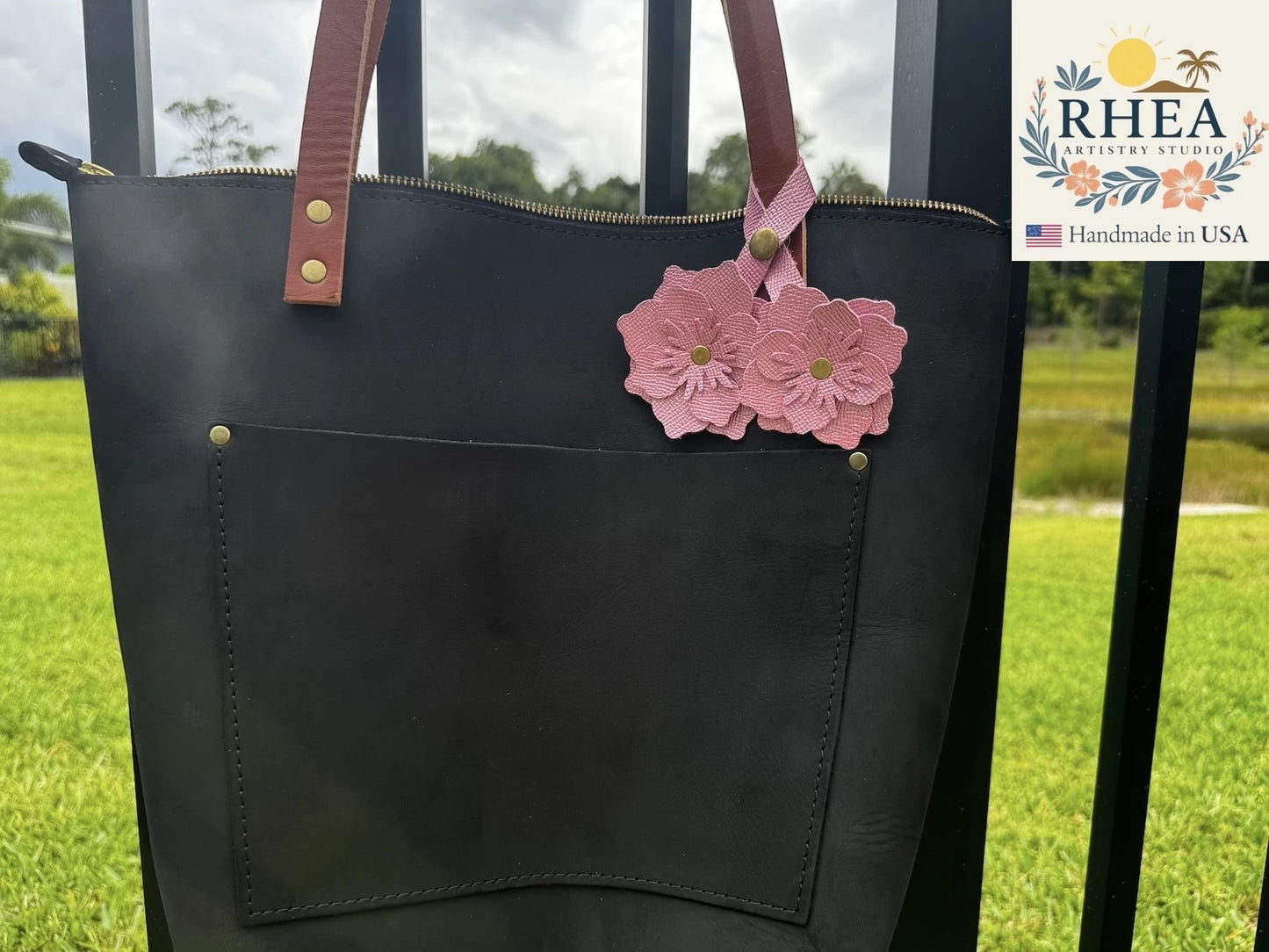 Rhea Artistry Studio Barbie Pink double leather flower charm with brass rivets, attached to a black leather tote bag.