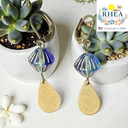 Rhea Artistry Studio blue faceted glass bead drop earrings with brushed brass teardrop charm, 2 inches long.