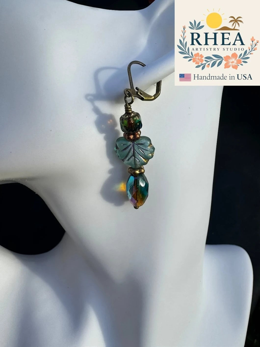 Rhea Artistry Studio handmade Czech glass earrings with blue leaf bead and iridescent drop, antique brass hardware, 2 inches long.