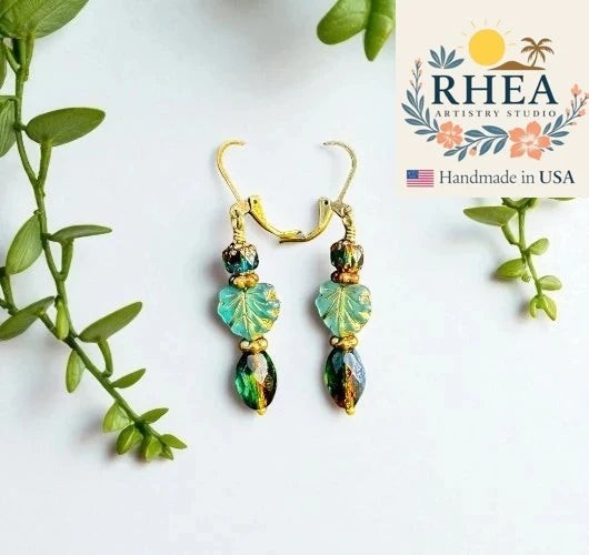 Rhea Artistry Studio handmade Czech glass drop earrings with green leaf beads and antique brass hardware.