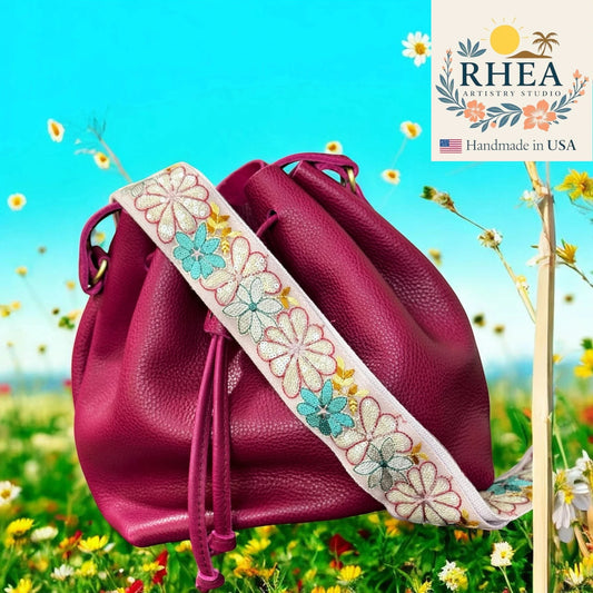 Rhea Artistry Studio 2-inch crossbody strap with embroidered white and blue daisies, made from lace and cotton webbing.