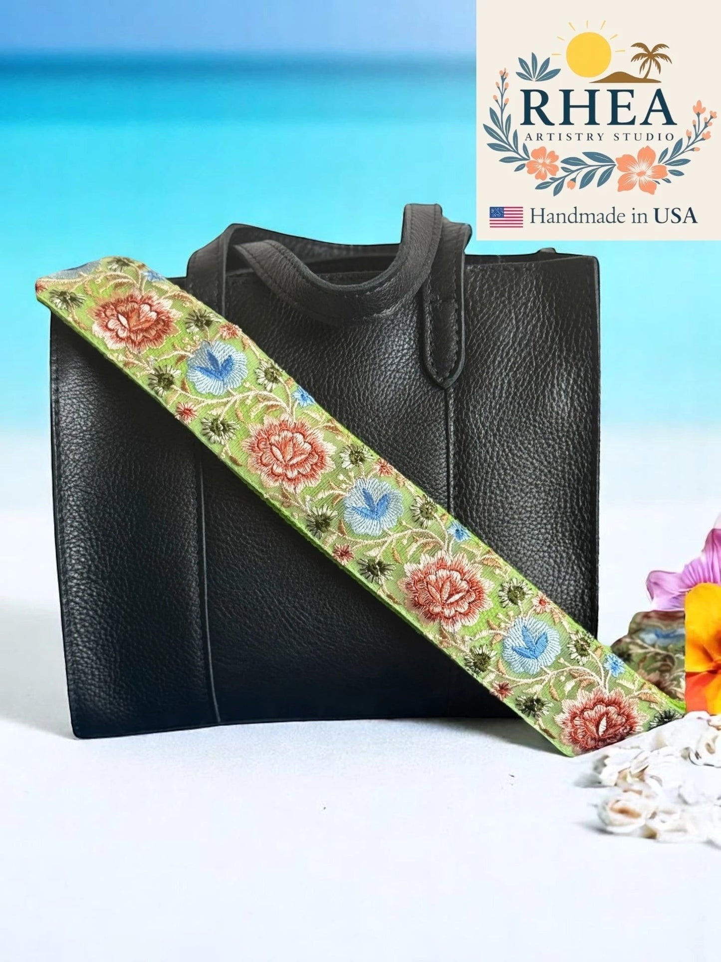 Rhea Artistry Studio 2-inch wide crossbody strap with green background and embroidered floral pattern in pink, blue, and coral. Adjustable length with brass hardware.