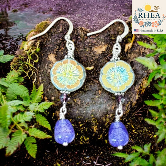 Rhea Artistry Studio Iris Glow Czech floral glass bead drop earrings with faceted purple gemstone teardrops and crystal accents.