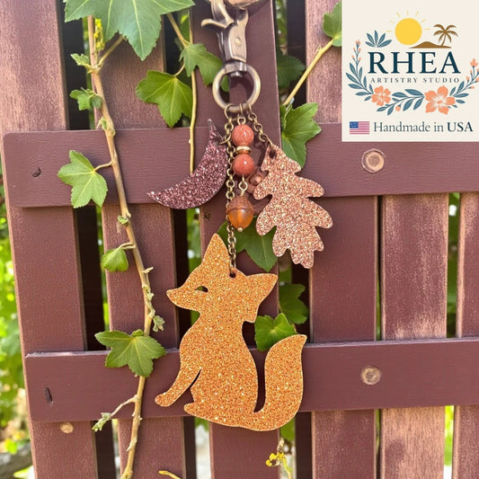 Rhea Artistry Studio handmade glitter leather fox charm with moon, oak leaf, acorn, and beads. Antique brass hardware.