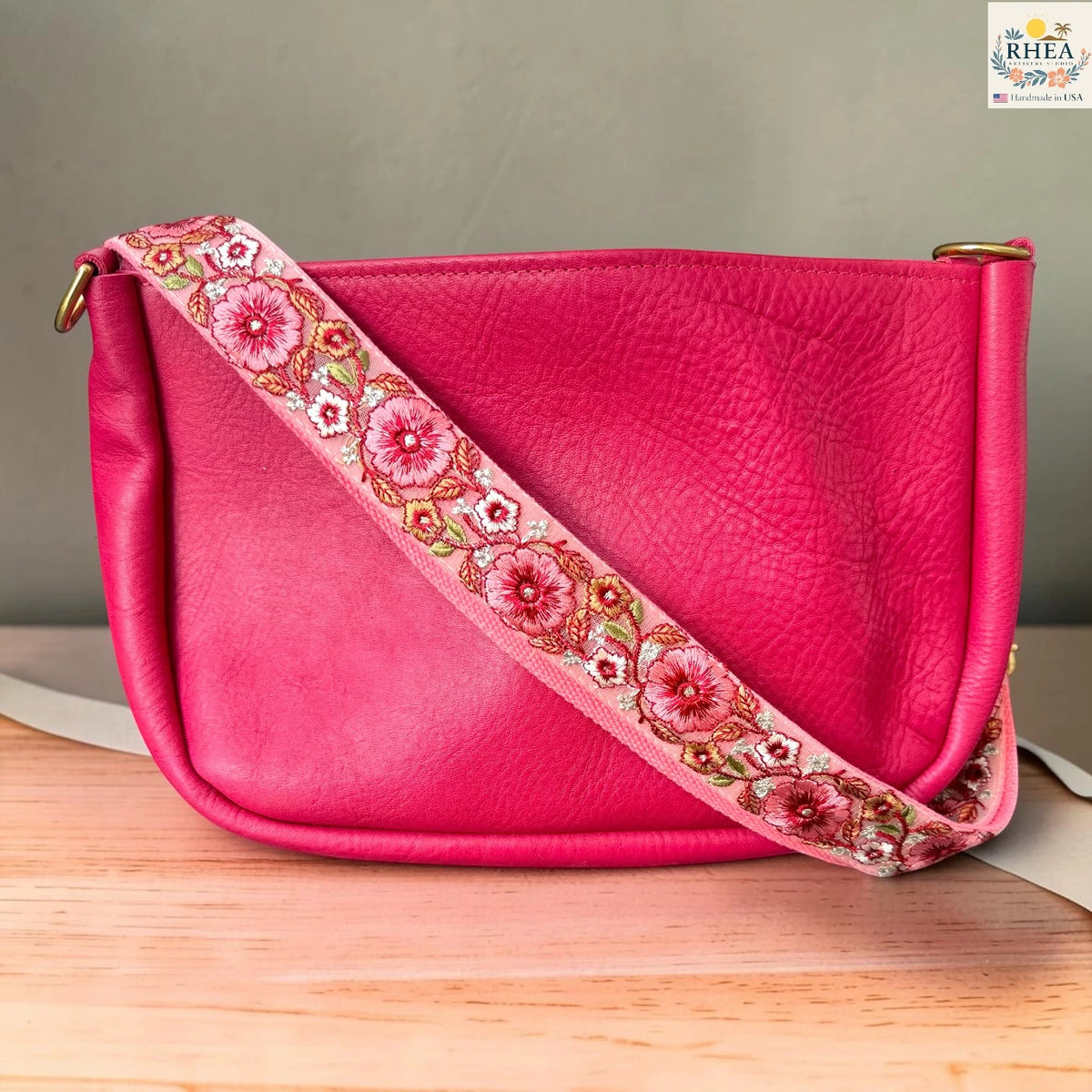 Rhea Artistry Studio ivory crossbody strap with coral and red floral embroidery with green leaf accents, 1.5-inch width, adjustable length.