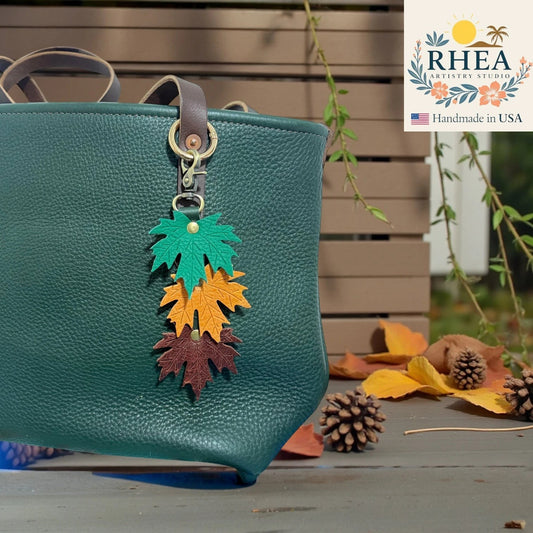 Rhea Artistry Studio layered maple leaf leather bag charm in green, orange, and brown with vein detail and brass hardware.