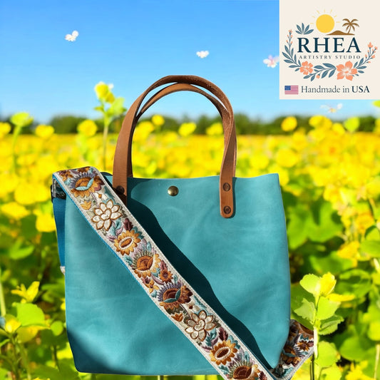 Rhea Artistry Studio teal leather tote bag with a 2-inch wide adjustable sunflower embroidered strap.