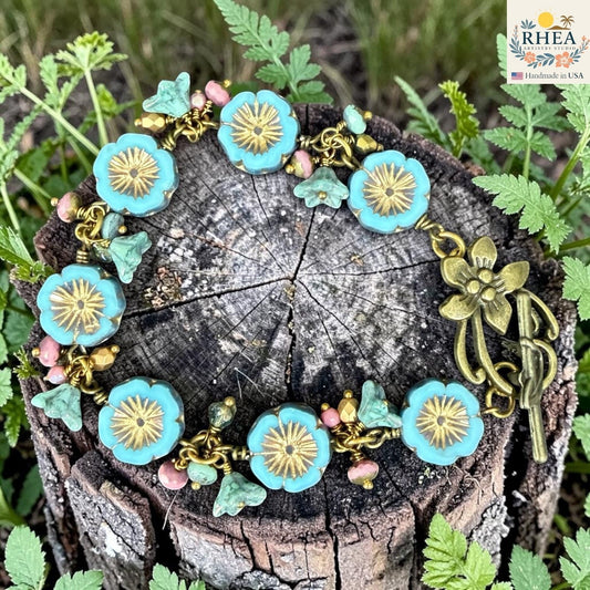 Rhea Artistry Studio handmade bracelet with turquoise flower glass beads, pink accent beads, and antique brass toggle clasp.