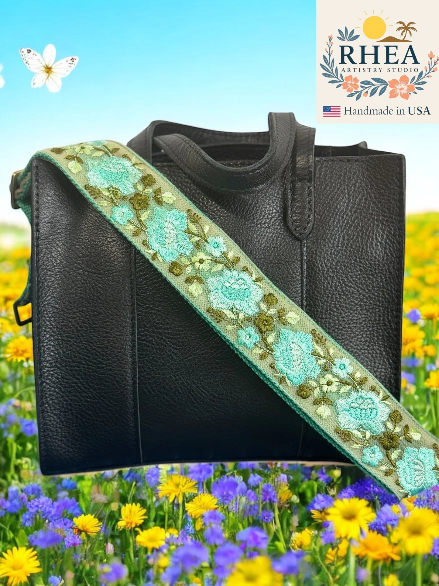 Black handbag with a floral embroidered purse strap against a colorful floral background, featuring the RHEA Artistry Studio logo.