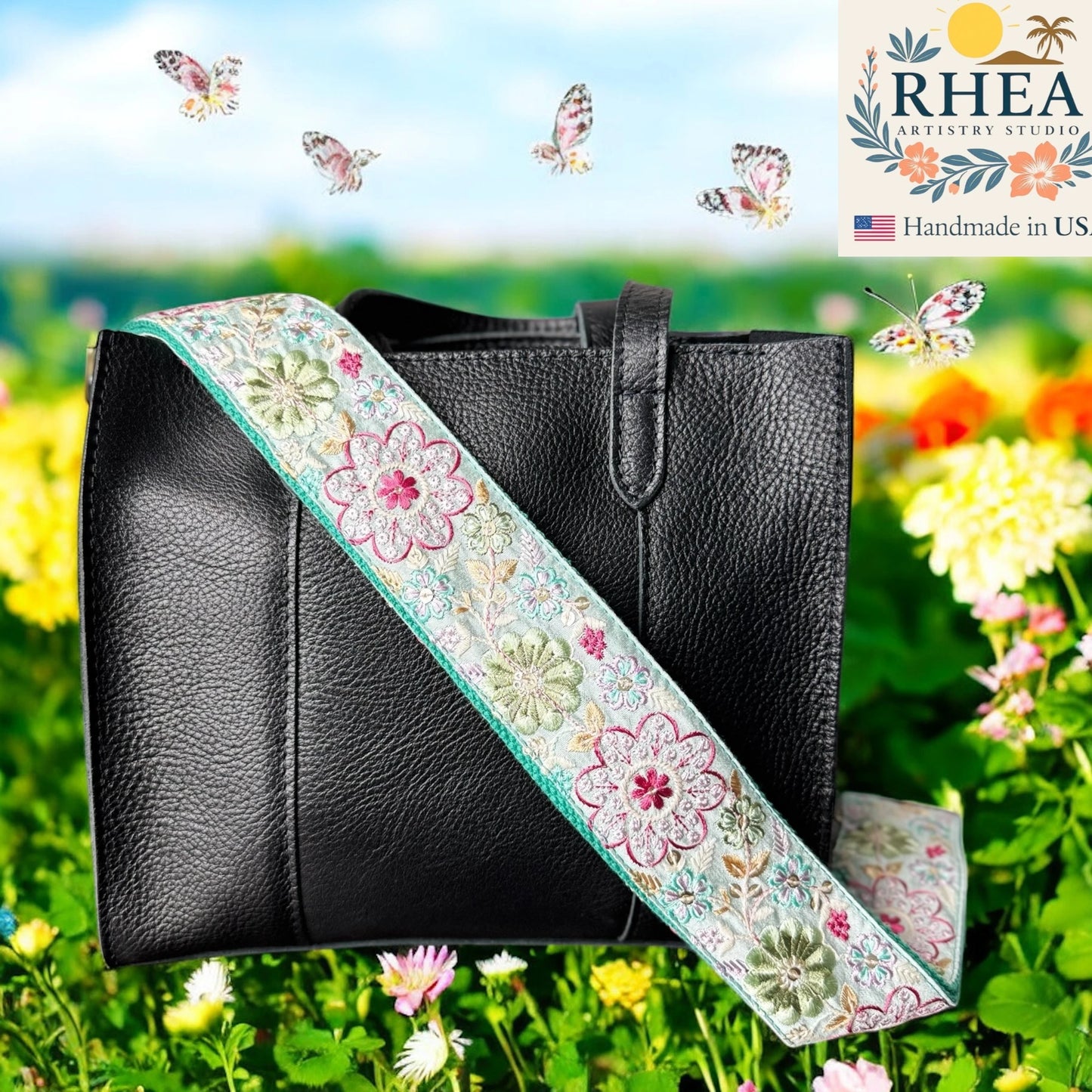 Black handbag with a floral purse strap against a colorful garden background, featuring the RHEA Artistry Studio logo.