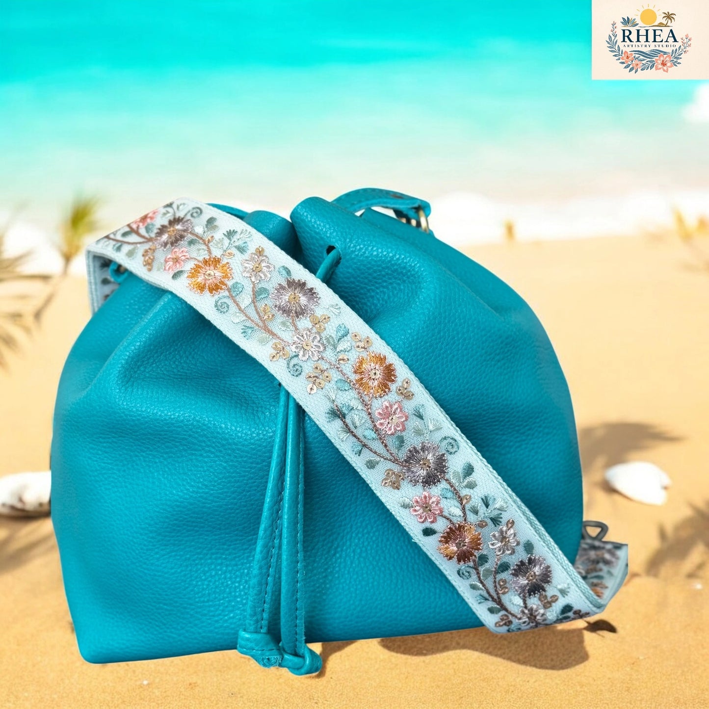 Blue drawstring bag with floral strap on a beach